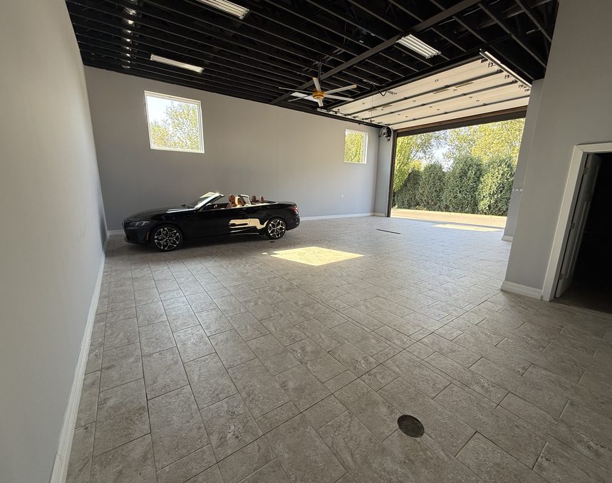 Inside the 3,400 square foot end unit: tiled floor, finished walls, a black convertible parked under the overhead door